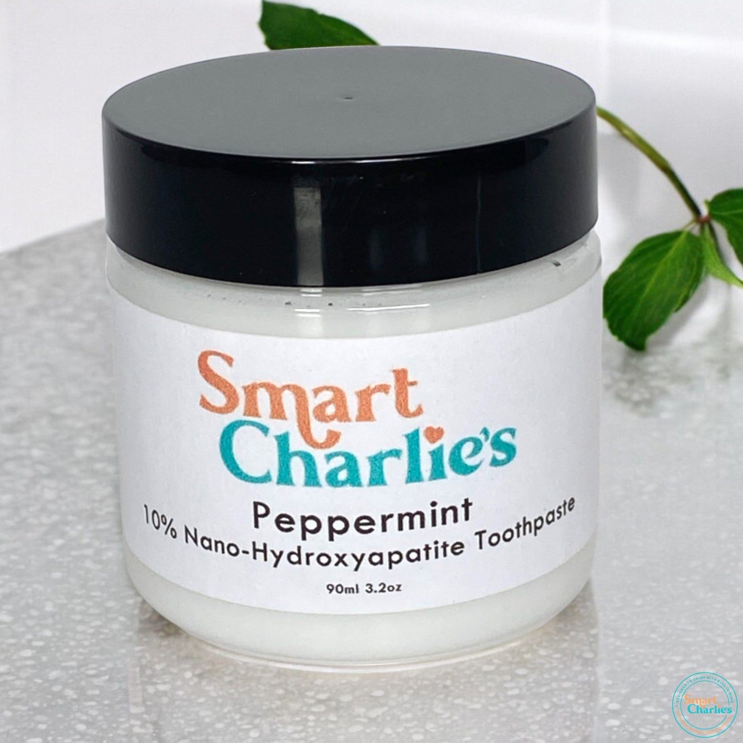Jar of Smart Charlie's peppermint toothpaste with a black lid on a white background